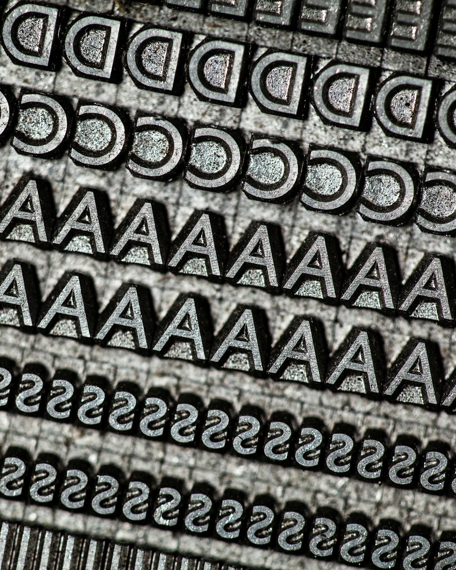 Rows of metal type sorts, a line of capital As between lines of Ds, Cs and Ss