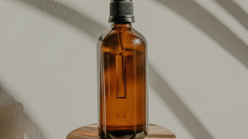An amber glass bottle on a wooden plinth in raking sunlight